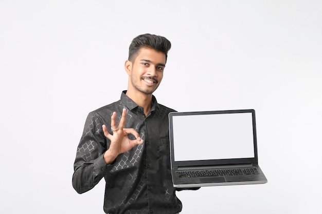 Jovem indiano mostrando a tela do laptop em fundo branco.