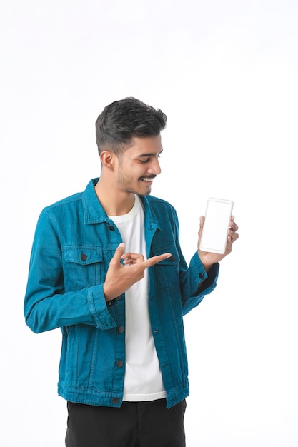 Jovem indiano mostrando a tela do smartphone em fundo branco.