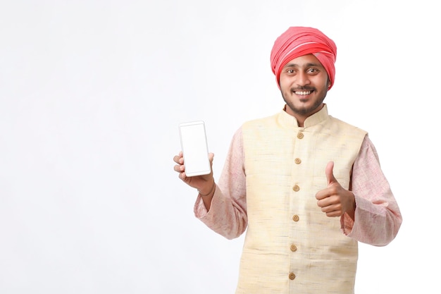 Jovem indiano mostrando smartphone e dando expressão em fundo branco.
