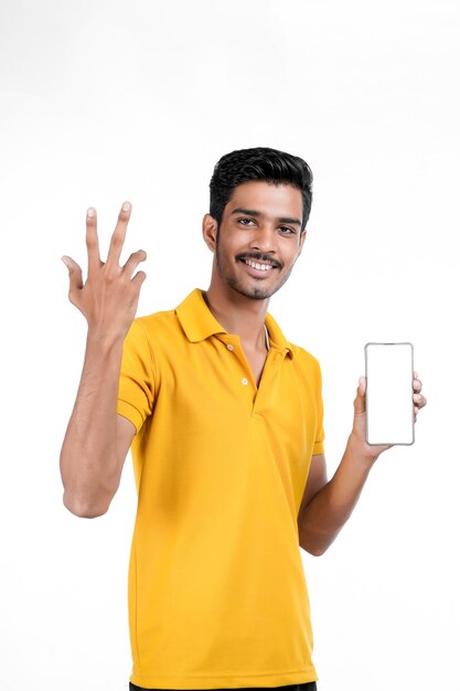 Jovem indiano mostrando smartphone em fundo branco
