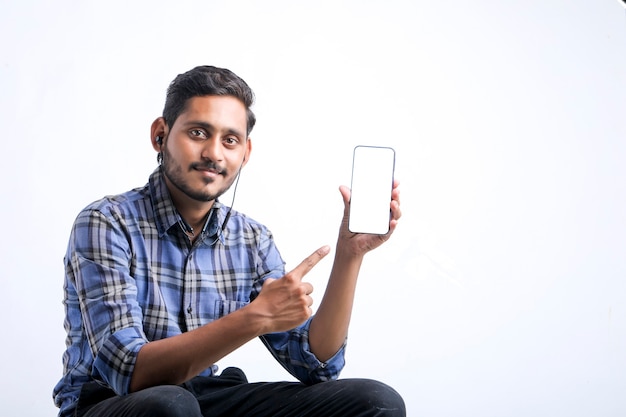 Jovem indiano mostrando Smartphone sobre fundo branco.