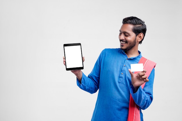 Jovem indiano mostrando tablet e cartão sobre fundo branco.