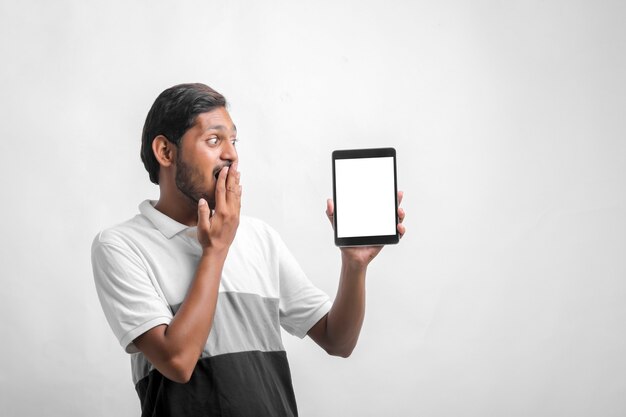 Jovem indiano mostrando tablet sobre fundo branco.