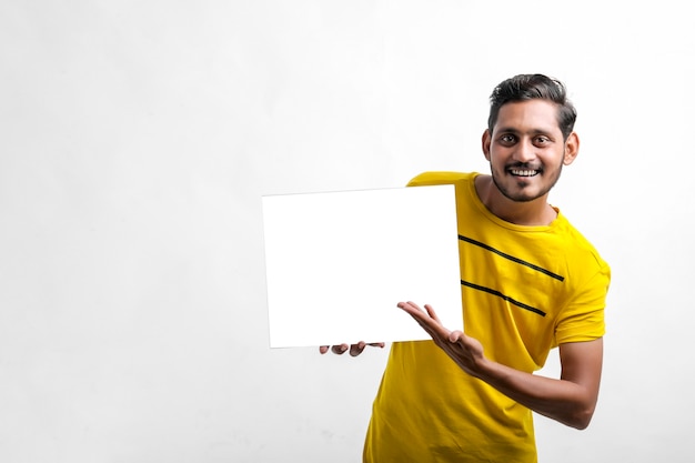 Jovem indiano mostrando uma placa em branco sobre fundo branco