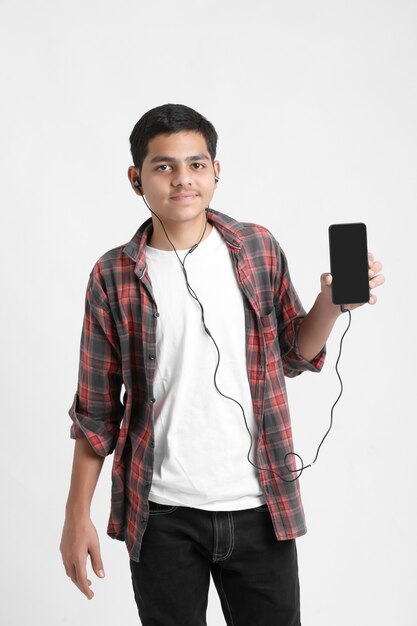 Jovem indiano ouvindo música e usando smartphone na parede branca