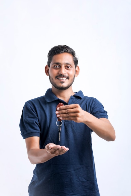Jovem indiano segurando a chave na mão sobre fundo branco.