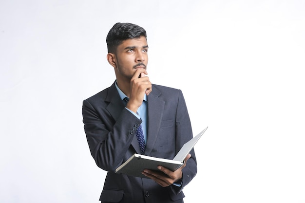 Jovem indiano segurando um diário e pensando em uma ideia