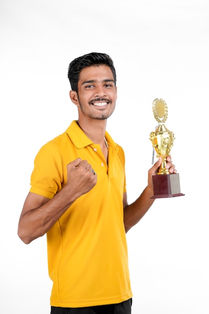 Jovem indiano segurando um troféu e fazendo gesto de vencedor