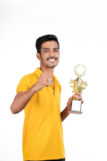 Jovem indiano segurando um troféu e fazendo gesto de vencedor