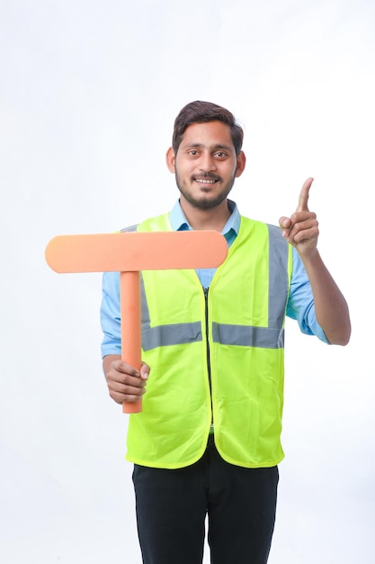 Jovem indiano segurando uma placa de sinal vazio no fundo branco. conceito de trabalho de construção