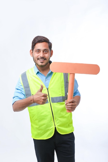 Jovem indiano segurando uma placa de sinal vazio no fundo branco. conceito de trabalho de construção