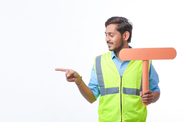 Jovem indiano segurando uma placa de sinal vazio no fundo branco. conceito de trabalho de construção