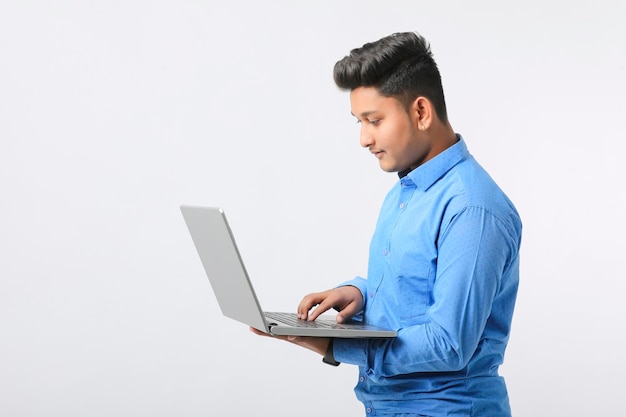 Jovem indiano usando laptop em fundo branco.