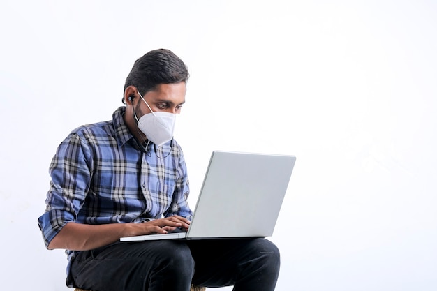 Jovem indiano usando laptop sobre fundo branco.