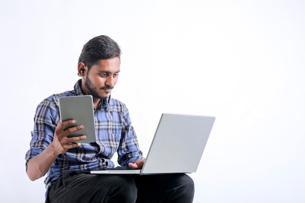 Jovem indiano usando laptop sobre fundo branco.