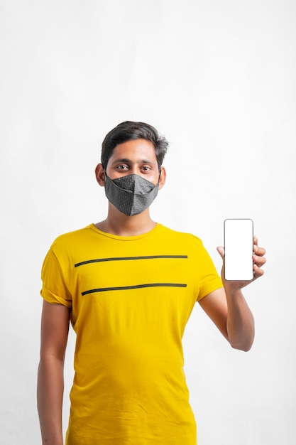 Jovem indiano usando máscara e mostrando smartphone