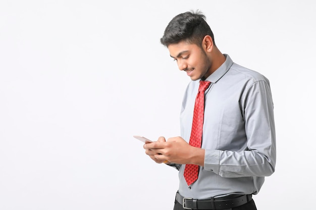 Jovem indiano usando smartphone e dando expressão em fundo branco.