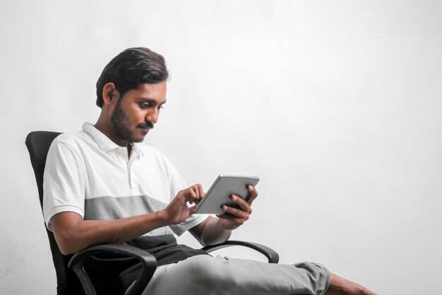 Jovem indiano usando tablet sobre fundo branco.