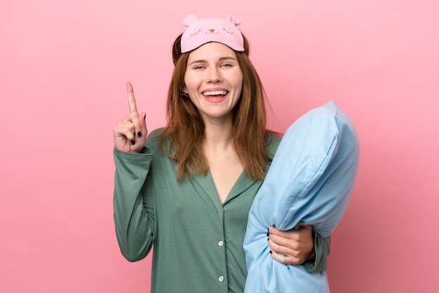 Foto jovem inglesa de pijama isolada em fundo rosa de pijama e apontando uma ótima ideia