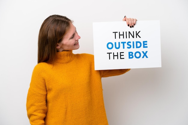 Jovem inglesa isolada em fundo branco segurando um cartaz com texto Think Outside The Box