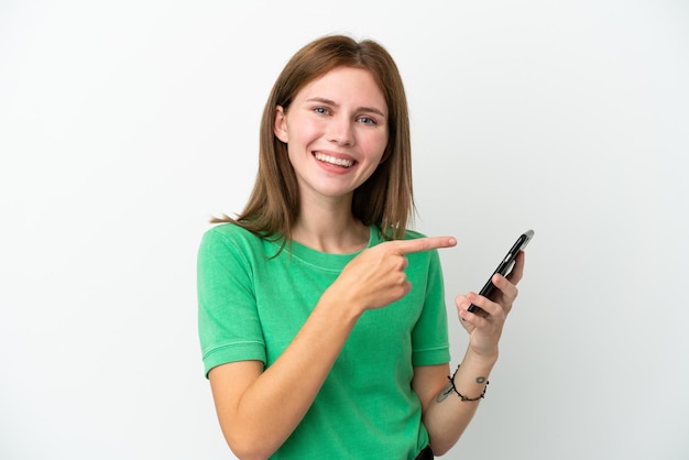 Jovem inglesa isolada em fundo branco usando telefone celular e apontando-o