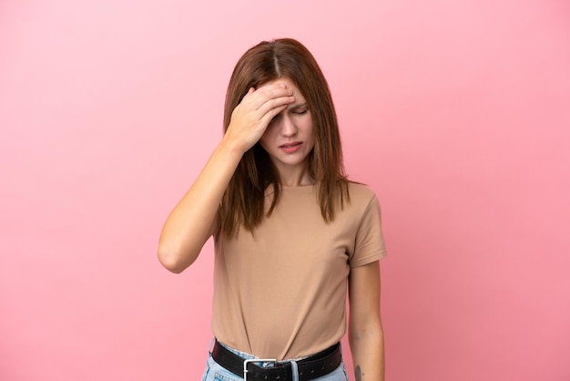 Jovem inglesa isolada em fundo rosa com dor de cabeça