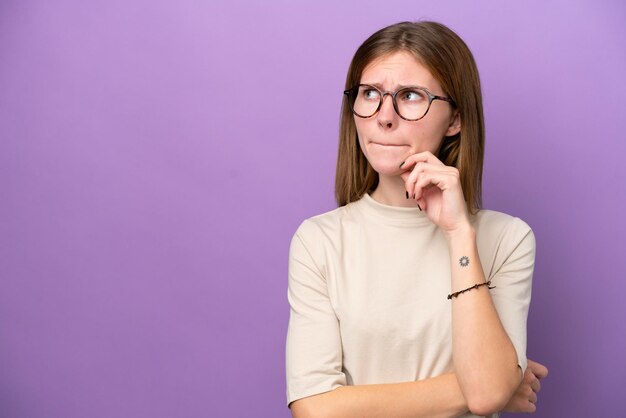 Jovem inglesa isolada em fundo roxo com dúvidas e pensando