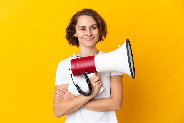 Jovem inglesa isolada no espaço amarelo segurando um megafone e sorrindo