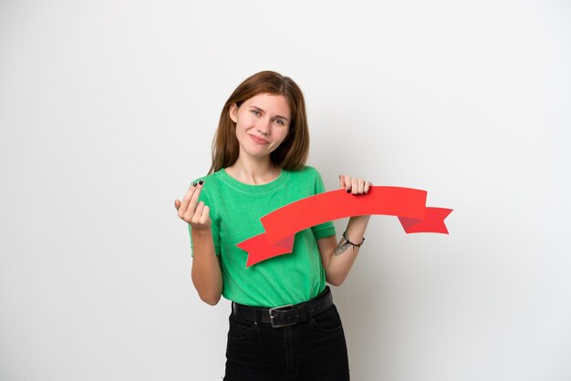 Jovem inglesa isolada no fundo branco segurando um cartaz vazio e fazendo gesto de chegada