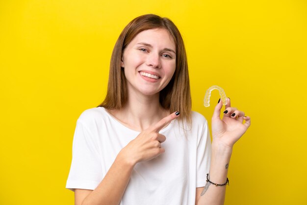 Jovem inglesa segurando aparelho invisível apontando para o lado para apresentar um produto