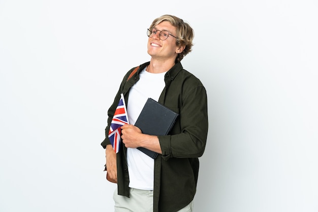 Jovem inglesa segurando uma bandeira do reino unido, posando com os braços na cintura e sorrindo