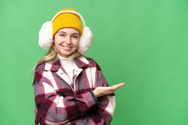 Jovem inglesa vestindo regalos de inverno sobre fundo isolado, apresentando uma ideia enquanto sorria para