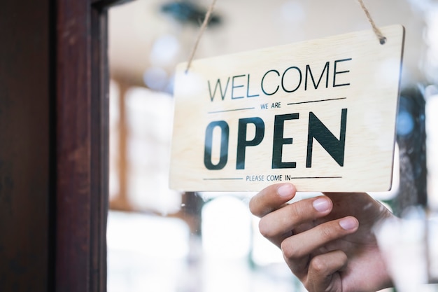 Jovem inicialização café café owener aberto e bem-vindo cliente.