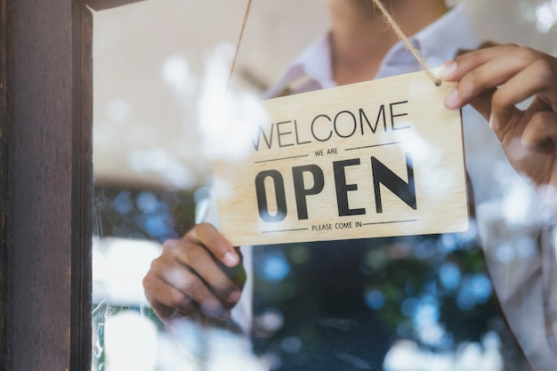 Jovem inicialização café café owener aberto e bem-vindo cliente.