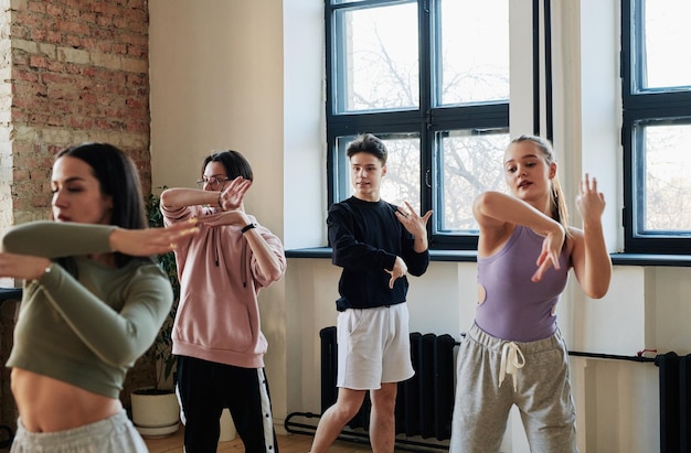 Jovem instrutor masculino do grupo de dança vogue consultando adolescentes e caras