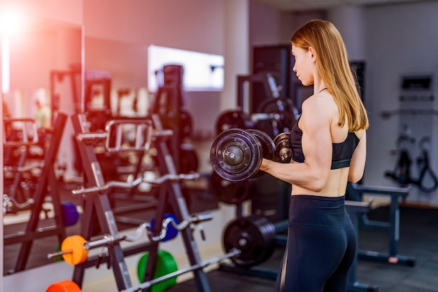 Jovem instrutora de fitness sexy se exercitando na academia Garota fitness se exercitando com barra na academia