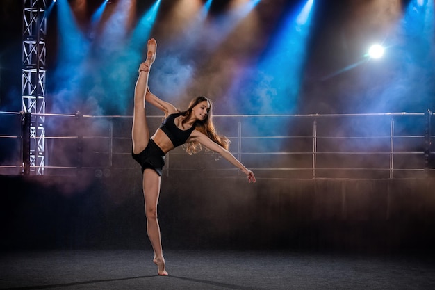 jovem intérprete de coreografia moderna dançando nos holofotes em um fundo preto