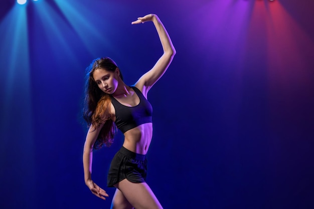 Foto jovem intérprete de coreografia moderna dançando nos holofotes em um fundo preto