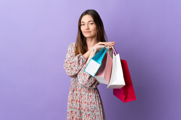 Jovem irlandesa isolada em um fundo roxo segurando sacolas de compras