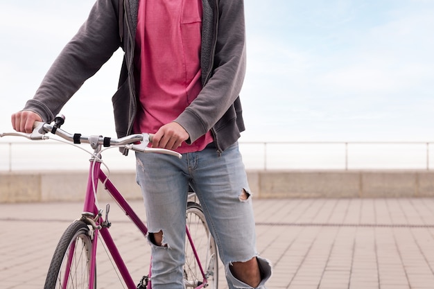 Jovem irreconhecível caminhando com uma bicicleta vintage