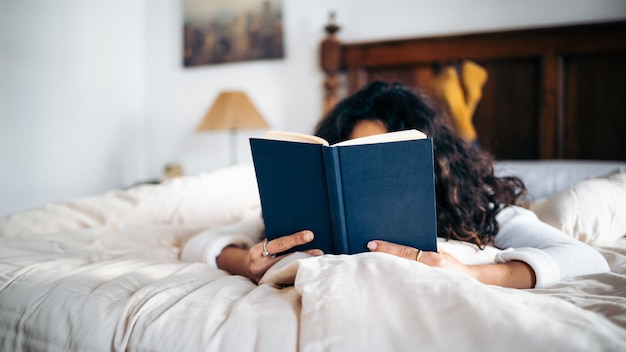 Jovem irreconhecível lendo um livro na cama