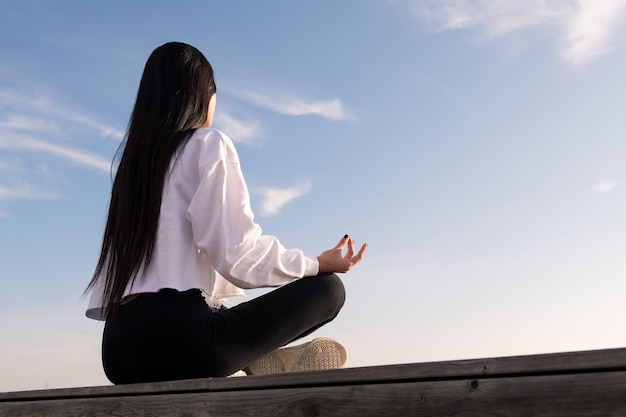 Jovem irreconhecível meditando ao nascer do sol