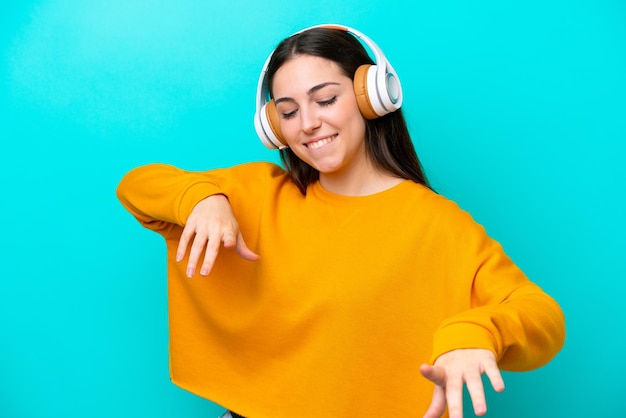 Jovem isolada em fundo azul ouvindo música e dançando