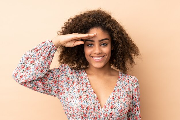 Foto jovem isolada na parede bege saudando com mão com expressão feliz