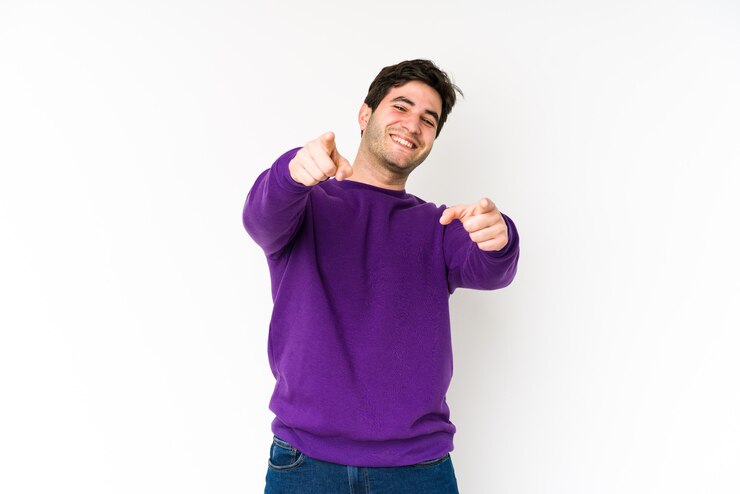 Foto jovem isolado em sorrisos alegres brancos, apontando para a frente.