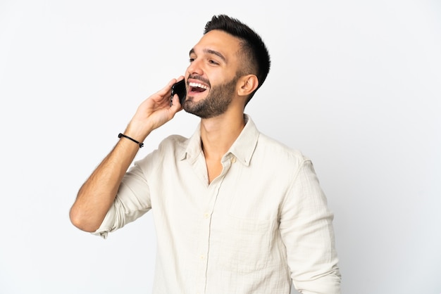 Jovem isolado na parede branca, conversando com alguém ao telefone celular