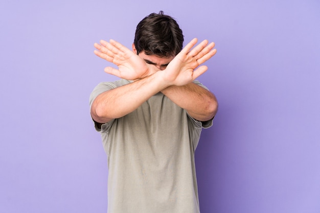 Jovem isolado no roxo, mantendo os dois braços cruzados, conceito de negação.