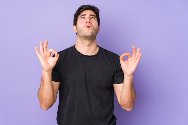 Jovem isolado no roxo relaxa após um duro dia de trabalho, ela está realizando ioga.