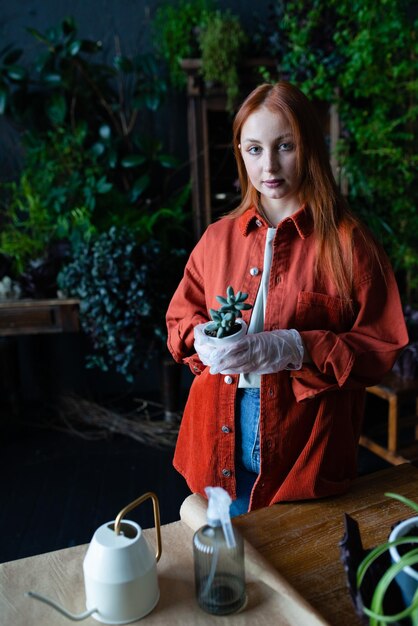 Jovem jardineira ou florista segurando uma flor na estufa olhando para a câmera