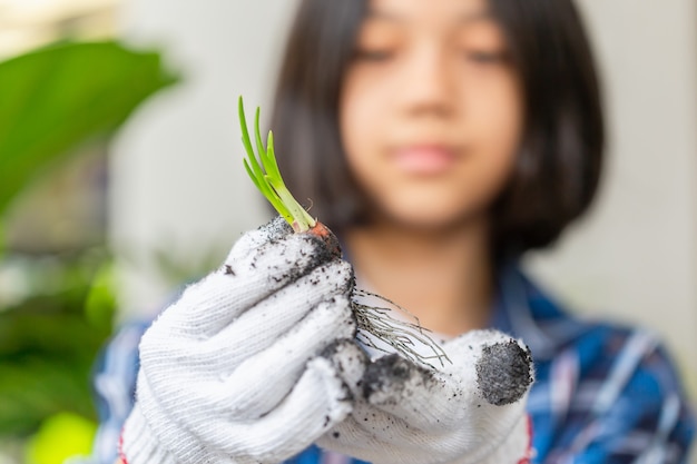 Jovem jardineira segurando plantas de cebola roxa, kid cuida de plantas jovens de cebola roxa, conceitos de plantas em crescimento